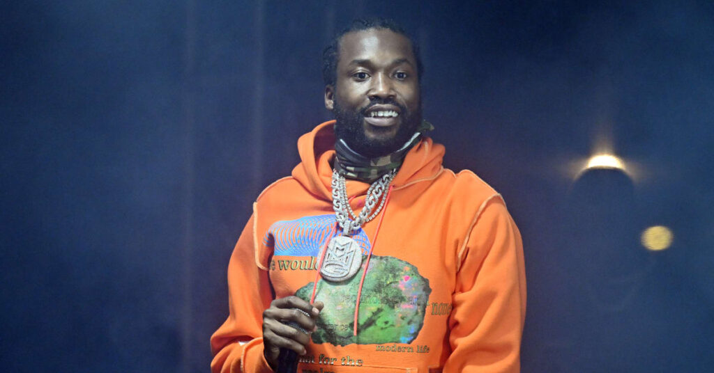 Meek Mill on stage, holding a microphone.
