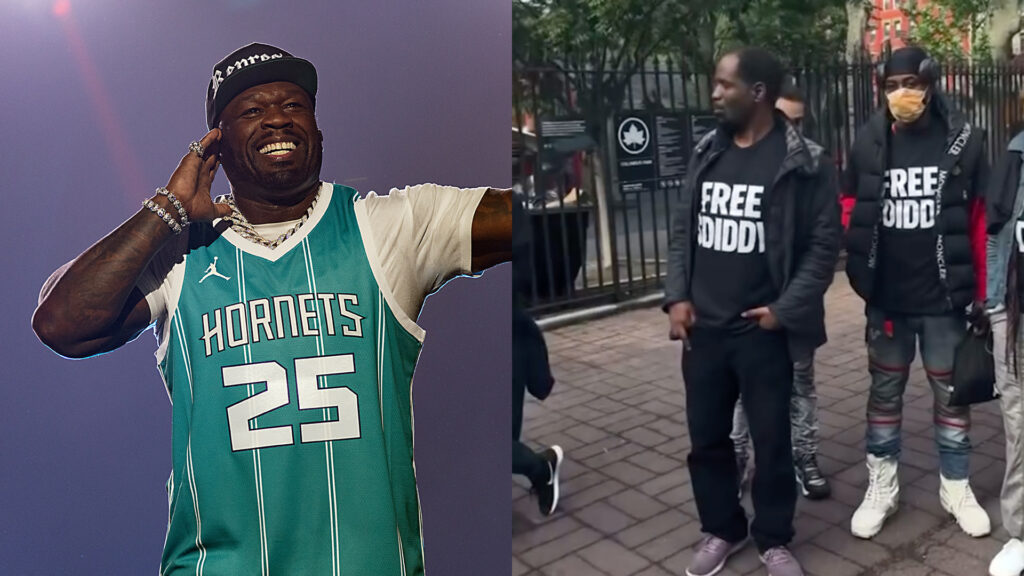 Rapper 50 Cent performs on stage wearing a teal Hornets jersey and black cap, holding a microphone, smiling and gesturing.