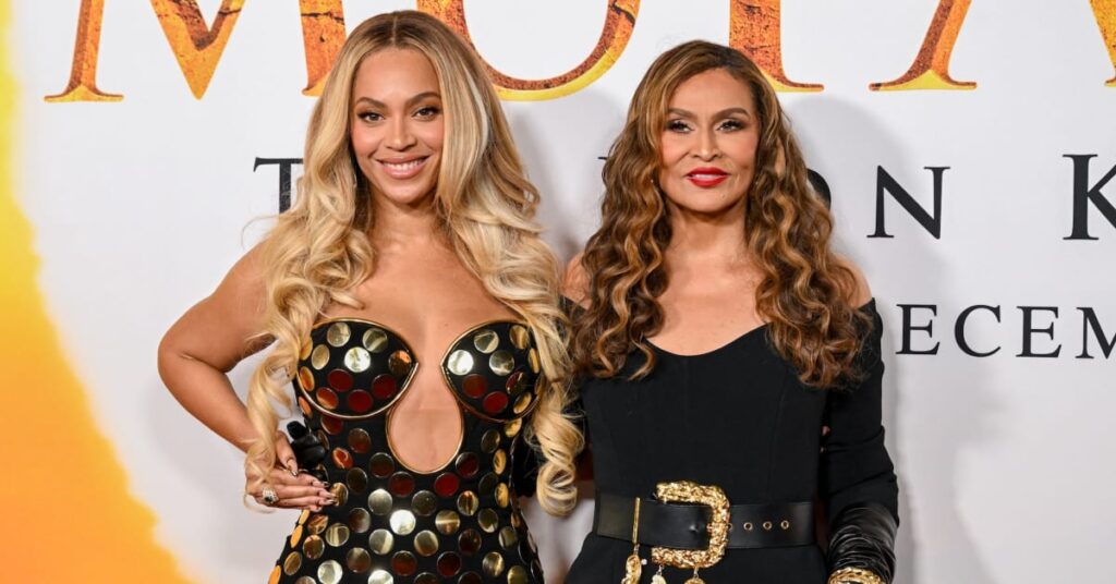 Beyoncé, wearing a black and gold dress, stands with Tina Knowles, in a black outfit, at an event.