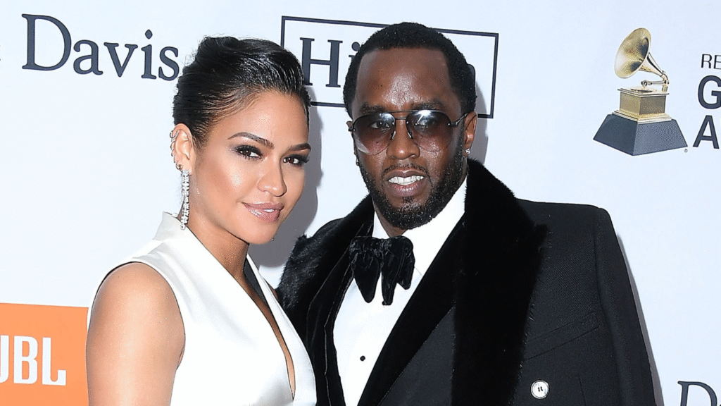 Cassie in a white dress and Sean "Diddy" Combs in a tuxedo with sunglasses at a red carpet event.