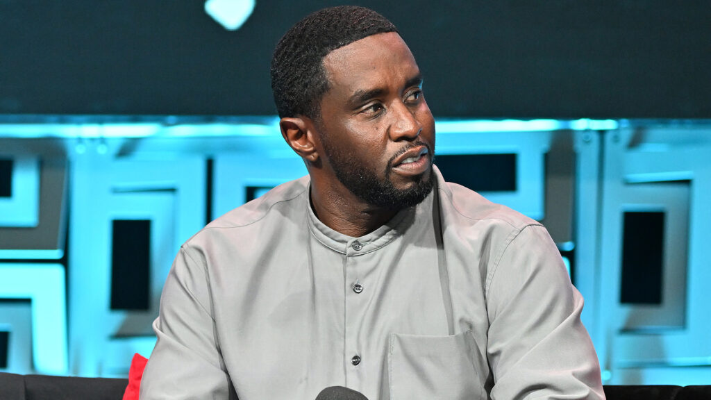 Diddy’s Legal Team Wants Expert Witness ‘Junk Science’ Te… Sean "Diddy" Combs in a gray shirt, seated on a stage, looking to the side.