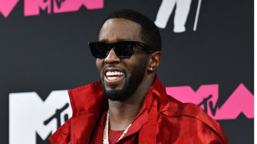 Sean "Diddy" Combs wearing sunglasses and a red outfit, smiling at an MTV event.