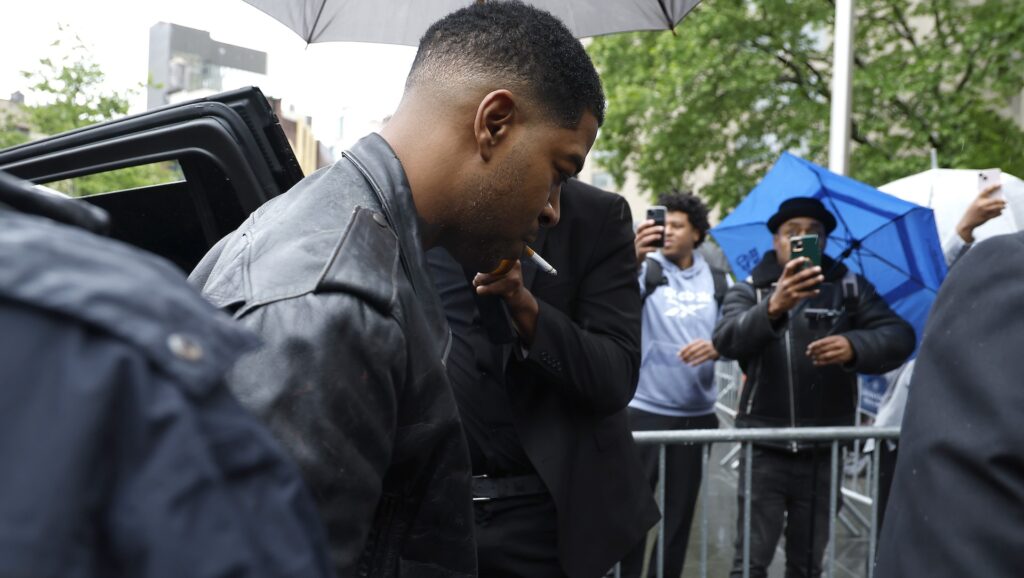 Kid Cudi Testifies About Diddy Blowing Up His Porsche: ‘W… Kid Cudi in a leather jacket is surrounded by people with umbrellas. Others are taking photos with their phones.