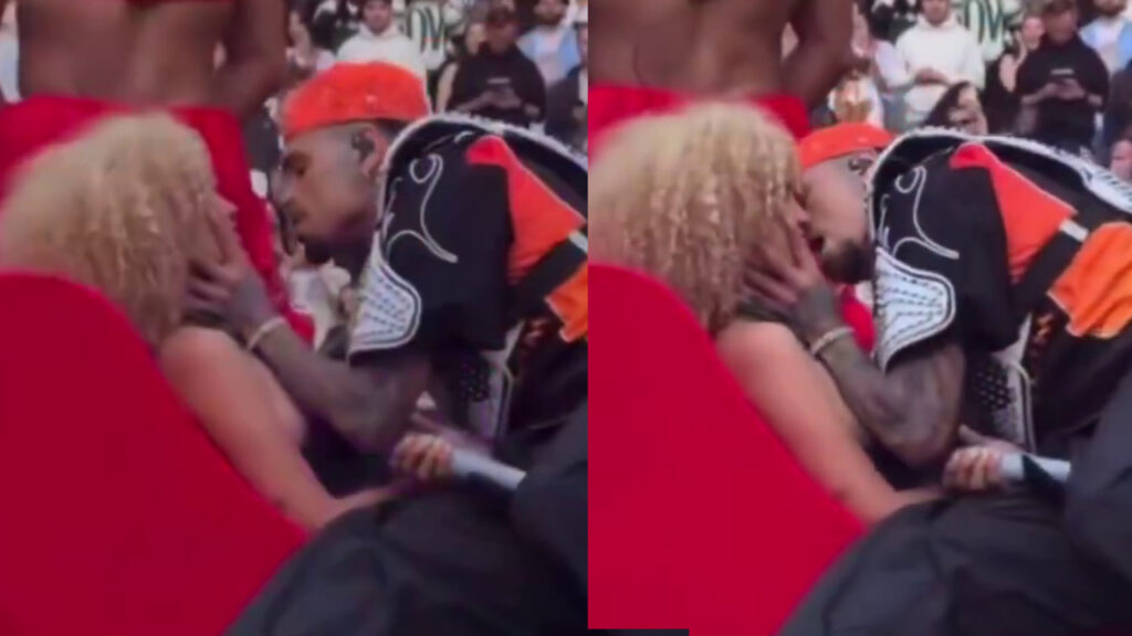 Chris Brown Kisses Fan After Giving Her Lap Dance During … Chris Brown on stage wearing a jacket with flame patterns, holding a microphone, with colorful lights and stairs in the background.