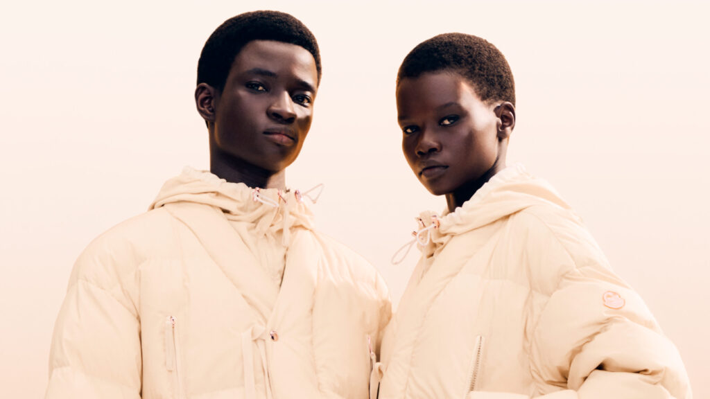 Donald Glover Designs New Moncler and Gilga Farm Collecti… Two models wearing matching light-colored puffer jackets, posing against a neutral background.