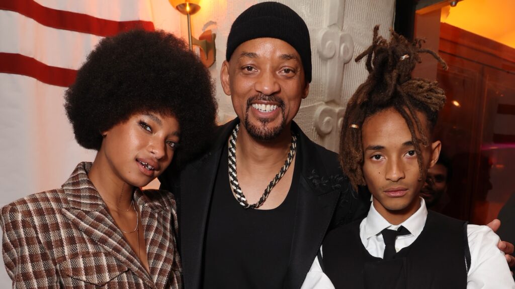 Willow Smith, Will Smith, and Jaden Smith smiling together at an event, with Willow and Jaden wearing stylish outfits.