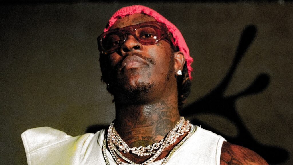 Young Thug, Yeat, More Confirmed for ComplexCon 2025: How… Young Thug wearing a pink bandana, sunglasses, and layered necklaces, looking upward.