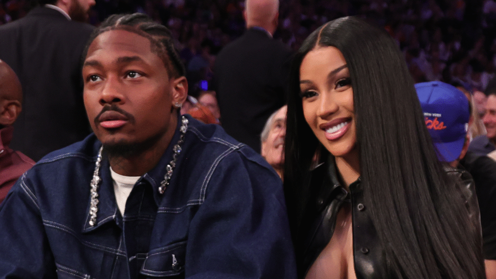 Two people sitting at a sports event, with the woman smiling.
