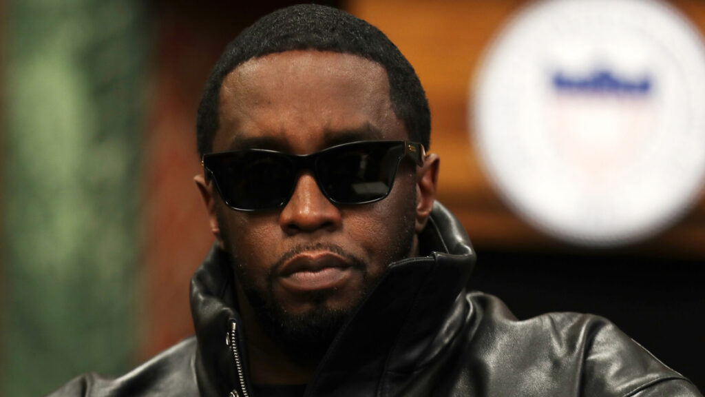 Sean "Diddy" Combs wearing sunglasses and a black leather jacket, looking serious.