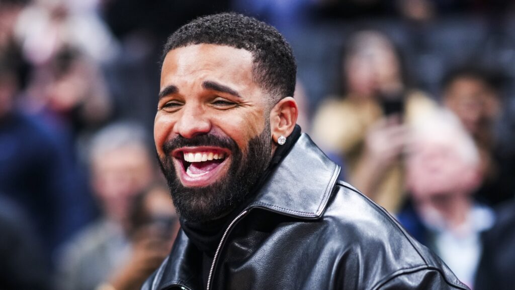 Drake laughing and wearing a black leather jacket.